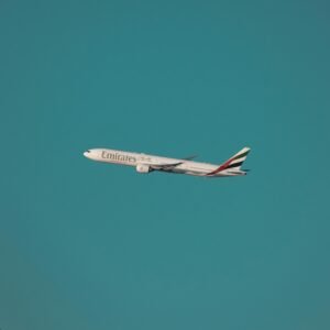 An Emirates airplane flying in a clear blue sky over Dubai, showcasing air travel and aviation.