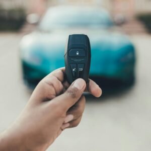 A close-up view of a hand holding a luxury car key with a blurred car in the background. Captured in New Delhi, India.